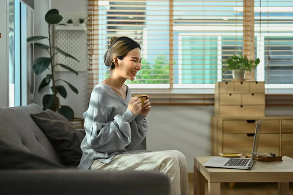 컴퓨터로 비디오 통화를 소파에서 커피를 마시는 여성의 — 스톡 사진