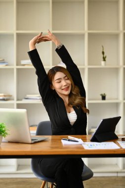 Rahatlamış ofis çalışanı kadın, kollarını uzatıyor, laptopla işe ara veriyor. İş yeri konseptinde yorgunluk nöbeti.