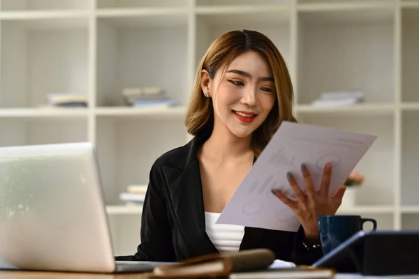 Accountant woman using laptop, working with financial graph chart report, preparing present at workplace.
