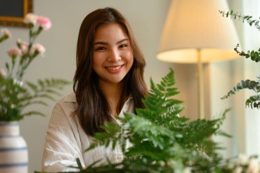 Güzel Asyalı kadın çiçekçi çiçekçide çiçekçide pembe çiçek buketi hazırlıyor..