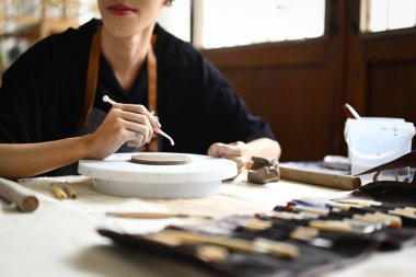 Atölyede yemek yapmadan önce çömlek dekore eden genç bir adam manzarası. Sanat, etkinlik, el işi ve hobiler.