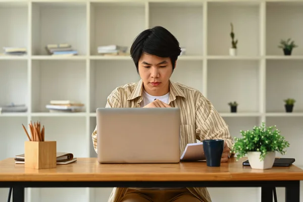 Skupiony Azjatycki Mężczyzna Przedsiębiorca Patrząc Ekranie Komputera Pisanie Ważnych Uwag — Zdjęcie stockowe