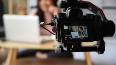Reklam sırasında oturma odasında dizüstü bilgisayar kullanan kadın modelli dijital kameranın yakın görüntüsü, kameraya odaklan.