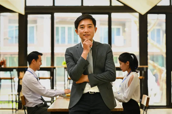 Portrait of asian millennial male executive wearing formal clothes standing and smiling confidently to camera.