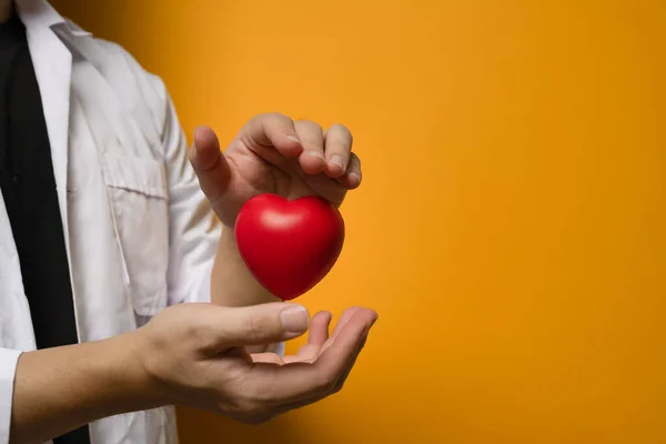 Ręce Trzymające Wskazujące Czerwone Serce Żółtym Tle Koncepcja Kardiologii Medycyny — Zdjęcie stockowe