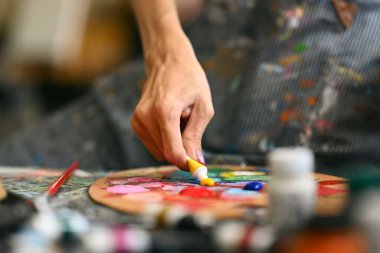 Erkek ressamın paletteki yağlı boyayı karıştırdığı yakın çekim görüntüsü. Sanat, hobi ve eğlence etkinliği konsepti.