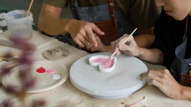 ワークショップでは エプロン塗装セラミックプレートに若い男の作物のショット 屋内生活活動 手工芸品 趣味の概念 — ストック動画