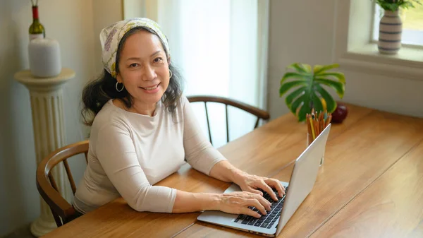 积极时尚的中年女性在舒适的家庭内部使用笔记本电脑 技术和生活方式概念 — 图库照片