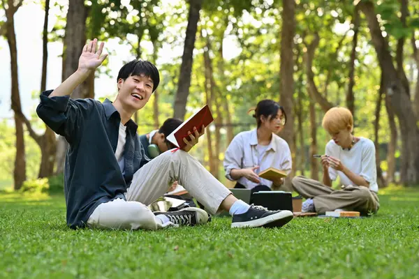 Sorrindo Asiático Homem Estudante Sentado Grama Verde Campus Com Amigos — Fotografia de Stock