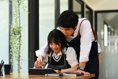 Küçük işletme sahipleri dijital tablet üzerinde çalışırken ve planlarken mutlu genç çiftler. Küçük işletme yönetimi kavramı.