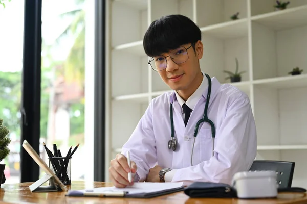 Retrato Médico Generalista Uniforme Branco Preenchendo Forma Médica Enquanto Sentado — Fotografia de Stock