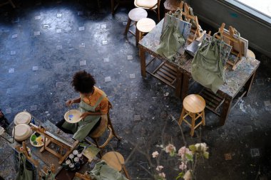 Genç Afrikalı Amerikalı kız öğrencinin tuvale resim çizmesi, sanat atölyesinde tek başına oturması..