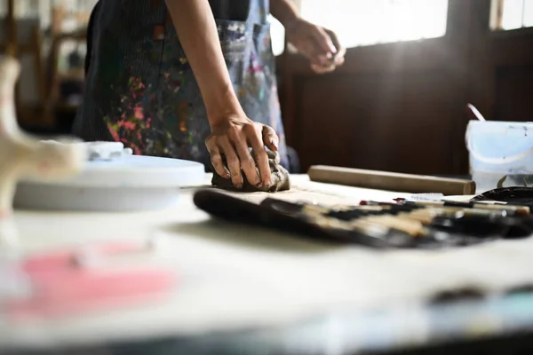 穿着围裙的女工匠用手在木制桌子上揉碎一块生粘土 手工艺 创造力 业余爱好和活动概念 — 图库照片