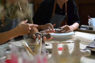 Ham kil şekillendirme ve süsleme ile çalışan yaratıcı stüdyodaki çömlek sanatçısı resmi.