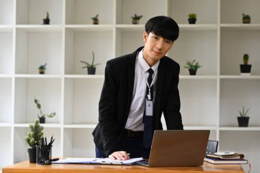 Yakışıklı erkek yönetici resmi kıyafetler giyiyor ve kameraya güvenle gülümsüyor..