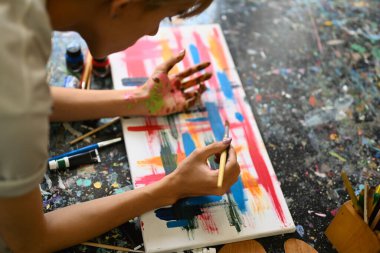 Parlak sanat stüdyosunda yağlı boyalarla tuvale resim yapan konsantre bir adam. Boş zaman aktivitesi ve sanat konsepti.