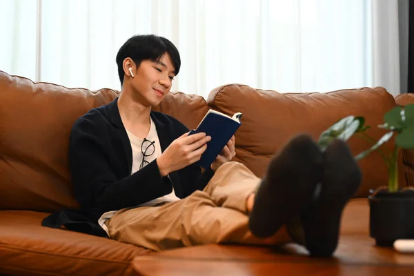 Relaxado Asiático Homem Ler Livro Sofá Sala Estar Conceito Pessoas — Fotografia de Stock