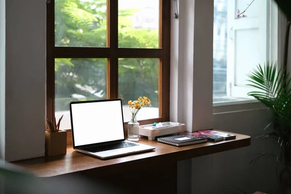 快適なホームインテリア ウィンドウ近くの木製の机の上に空白のディスプレイ 文房具付きのラップトップ — ストック写真
