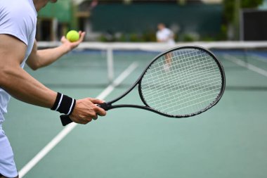 Tenis oyuncusu açık kortta oynanan bir maçta tenis topu servis ediyor. Spor, eğitim ve aktif yaşam konsepti.