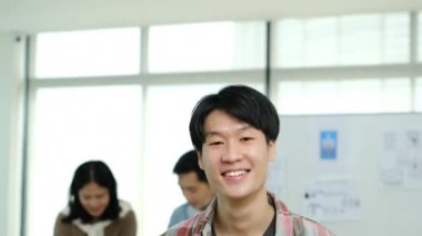 Asyalı erkek web geliştiricisinin dijital tablet tutarken ve kameraya gülümserken çekilen görüntüsü..