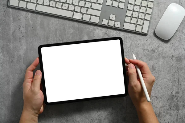 stock image From above view of man hand holding digital tablet with white empty display on gray stone table.