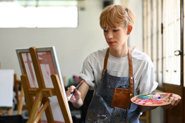 Yaratıcı genç Asyalı eşcinsel bir adam tuvalde yeni bir resim yapıyor. Sanat ve eğitim kavramı.