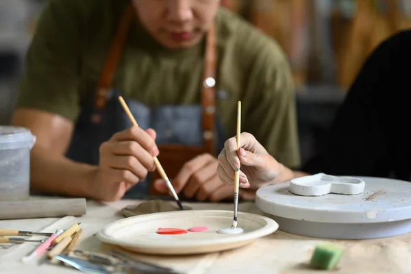 Konzentrierter Mann Bemalt Tonteller Mit Pinsel Schreibtisch Keramikwerkstatt — Stockfoto