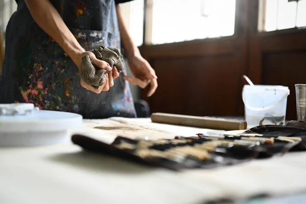 围裙上的陶艺家用手在木制桌子上揉碎一块生粘土 手工艺 创造力 业余爱好和活动概念 — 图库照片