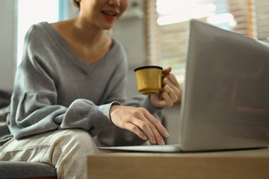 Evde dizüstü bilgisayar kullanan, sosyal ağda arkadaşlarıyla sohbet eden, film izleyen ve internetten alışveriş yapan mutlu genç bir kadın..