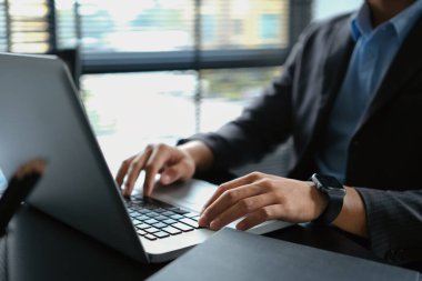 Profesyonel işadamı Hans dizüstü bilgisayarda yazı yazıyor, ofis masasında veri pazarı analizi yapıyor..