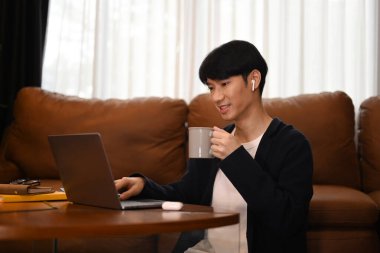 Şirin, yakışıklı, serbest çalışan, kahve içen uzaktan kumandalı, dizüstü bilgisayarla çalışan bir adam..