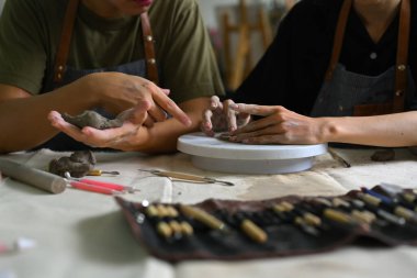 Usta seramistimizin kırpılmış görüntüsü öğrencilere sanat atölyesinde çamurdan el yapımı tabak yapımında yardımcı oluyor..