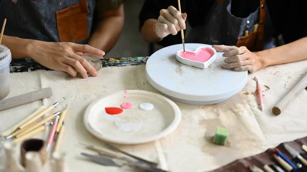 两个富有创意的年轻人在车间装饰手工制作的菜肴 手工艺 创造力和业余爱好概念 — 图库照片