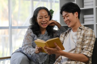 60 'lı yılların büyükannesi olan gülümseyen Asyalı genç adam kitap okuyor, evde vakit geçirmenin keyfini çıkarıyor. Nesil, aile ve aşk.