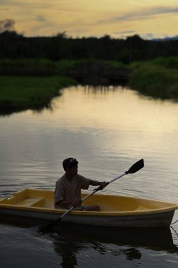 Güzel altın gün batımlı sakin suda kürek çeken bir adam silueti. Seyahat, yalnızlık, sakinlik ve rahatlama..