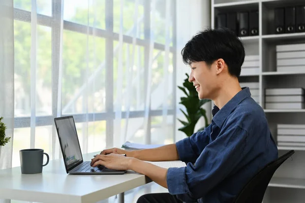 現代の職場でラップトップを使用してオンラインデータ市場分析を行うアジアの男性起業家 — ストック写真