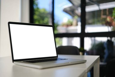 Ofis masasında beyaz boş ekran olan yakın plan dizüstü bilgisayar. Reklam metniniz için boş ekran. 