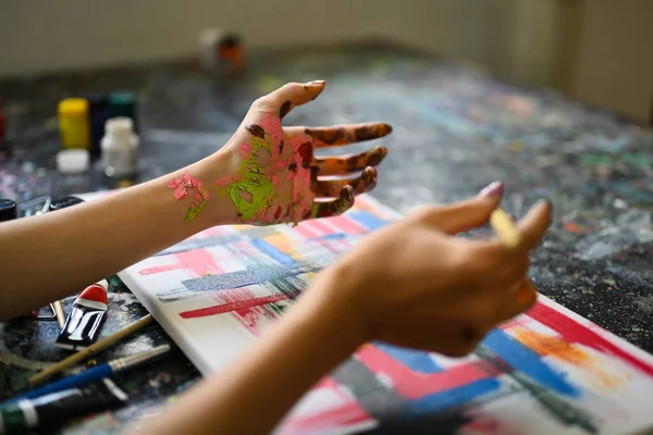 キャンバス上の絵筆と水彩で汚れた手の絵画と女性アーティストの作物のショット — ストック写真