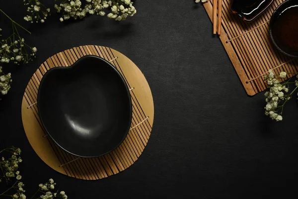 Boş siyah tabak ve kurumuş çiçekler menü, yemek tarifi ve restoran yemeği için siyah taş masaya..