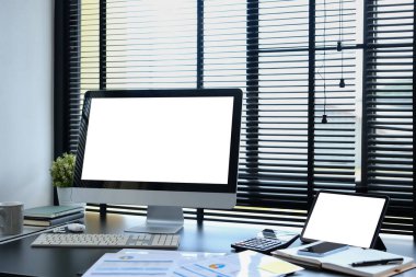 Modern ofis içi boş ekran bilgisayar, dijital tablet, belge ve malzemeler siyah ahşap masa üzerinde.