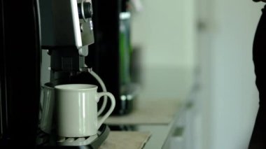 Slow motion shot of female office worker preparing fresh aromatic coffee, using a coffee machine maker in cozy office kitchen.