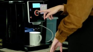 Tanımlanamayan bir kadın sıcak ofis mutfağında kahve makinesi kullanarak taze aromatik kahve hazırlıyor.. 