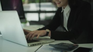 Profesyonel kadın muhasebeci masada oturuyor, dizüstü bilgisayarında daktilo yazıyor. İş teknolojileri kavramı.