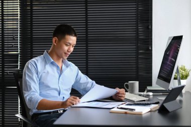 Milenyum işadamı, modern işyerinde ekonomi raporunu hazırlayan grafikleri ve grafikleri analiz ediyor..