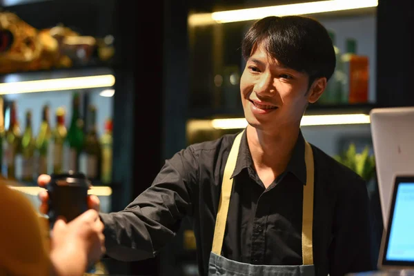 Handsome asian man barista serving coffee to customer. Start up, small business owner, food and drink concept.
