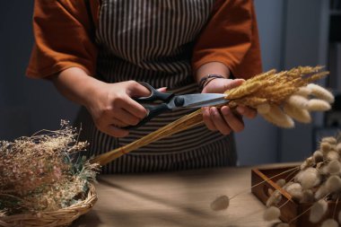Çiçekçinin atölyesinde kurutulmuş çiçek buketi yaparken çekilmiş bir fotoğrafı. Küçük işletme kavramı.