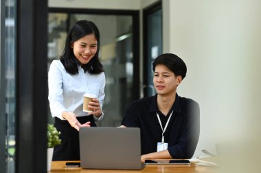 Dost canlısı bayan yönetici, iş arkadaşıyla bilgisayardaki satış istatistiklerini analiz ederek bilgiyi açıklıyor..