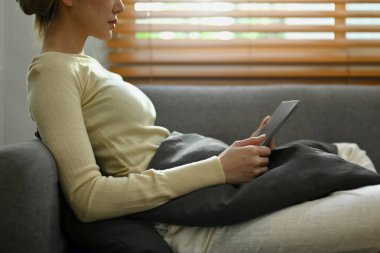 Sıradan genç bir kadın sosyal medyayı kontrol ediyor, dijital tablette internete takılıyor. Teknoloji, iletişim ve yaşam tarzı.