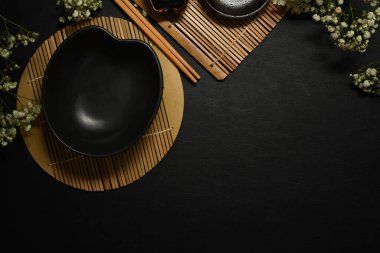 Koyu beton arka planda çatal bıçak takımı olan boş bir siyah tabak. Menü, yemek tarifi ve restoran yemeği için yer.