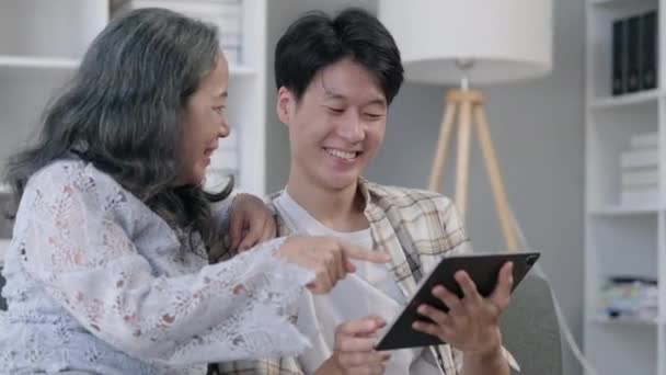 소파에 집에서 디지털 태블릿을 즐거운 아시아 남자와 할머니의 슬로우 모션에서 — 비디오